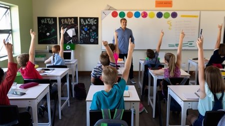 male-school-teacher-standing-in-an-elementary-scho-KC35YSL-1